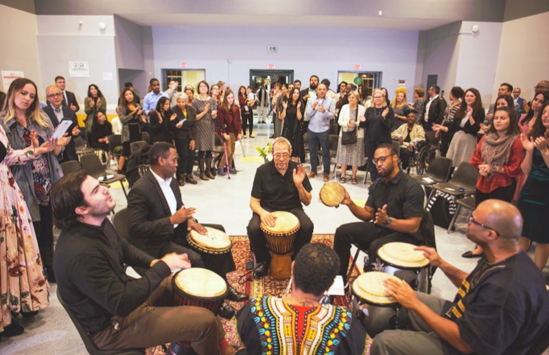 Bahá’í devotional, a group of people playing djembes