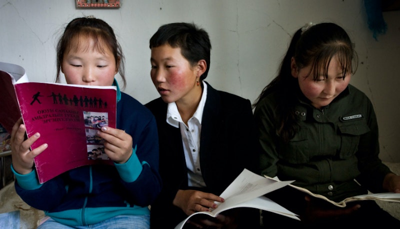 Three children looking over Ruhi material